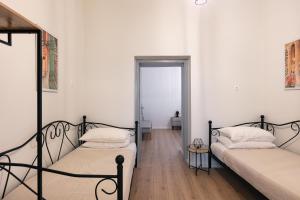 two beds in a room with white walls and wooden floors at Centro Storico in Chania Town