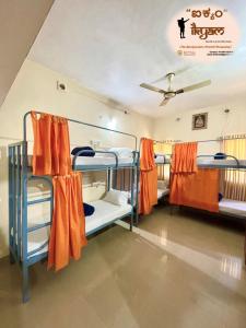 um quarto com 3 beliches com cortinas cor de laranja em iKyam (The Backpackers Hostel/Homestay) em Madikeri