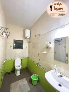 a green bathroom with a toilet and a sink at iKyam (The Backpackers Hostel/Homestay) in Madikeri