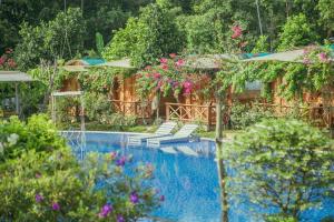 una piscina con sillas y árboles y flores en Phu Quoc Valley Sen Bungalow, en Phu Quoc