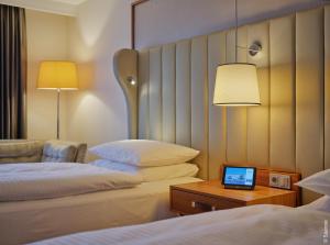 a hotel room with two beds and a laptop on a table at Dorint Hotel Bonn in Bonn