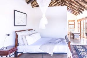 Cette chambre comprend un lit avec des draps blancs et un plafond en bois. dans l'établissement Des'lgodini Lodge - PRM078, à Bela-Bela