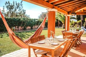een tafel met stoelen en een hangmat op een patio bij Villa Rosada - Private pool & Barbecue in San Jose de sa Talaia