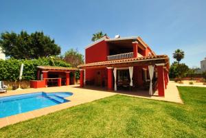 een rood huis met een zwembad in een tuin bij Villa Rosada - Private pool & Barbecue in San Jose de sa Talaia