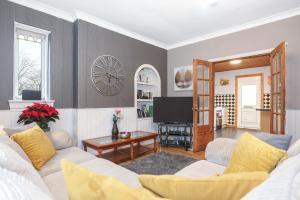 Beautiful 4 Bedroom Cottage - Free Parking في إدنبرة: غرفة معيشة مع أريكة وساعة على الحائط