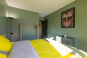 Un dormitorio con una cama amarilla con una foto en la pared en La Citadelle, en Nancy