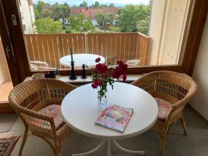 a white table with a vase of flowers on a balcony at Auszeit in Immenstaad am Bodensee +11 photos