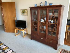 a living room with a television and a wooden cabinet at Auszeit in Immenstaad am Bodensee