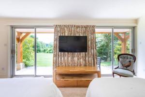 a living room with a tv and a large window at Dove Lodge in Painswick in Stroud