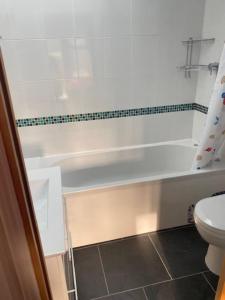 a bathroom with a white tub and a toilet at The Cart House - Staverton Cheltenham in Cheltenham