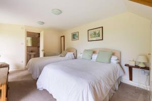 a bedroom with two beds with white sheets at Dove Lodge in Painswick in Stroud
