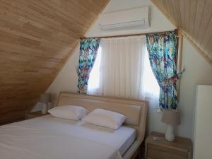 a bedroom with a bed with two pillows and a window at Bellerofon villa in Cıralı
