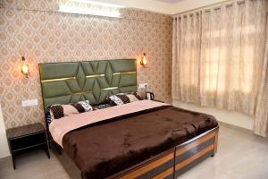 a bedroom with a large bed with a green headboard at Samriti Apartments in Shimla