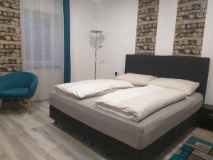 ein Schlafzimmer mit einem Bett und einem blauen Stuhl in der Unterkunft Sauna Fifty Rekreációs Szaunapark in Vaszar