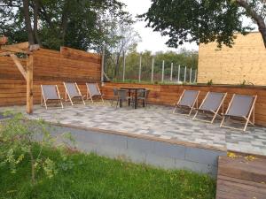 eine Terrasse mit Stühlen, einem Tisch und einem Zaun in der Unterkunft Sauna Fifty Rekreációs Szaunapark in Vaszar