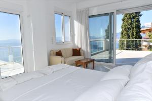 a white bedroom with a large bed and a balcony at Verga Villas Resort in Kalamata