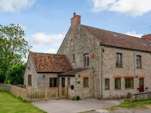 an old stone house with a wooden fence at Mulberry Cottage in North Wootton