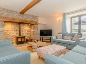 una sala de estar con sofás azules y una chimenea de piedra. en Mulberry Cottage, en North Wootton