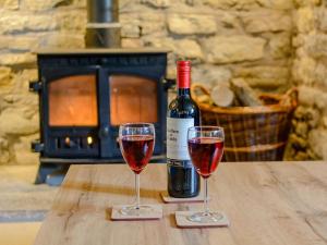 Dois copos de vinho tinto numa mesa de madeira. em Mulberry Cottage em North Wootton