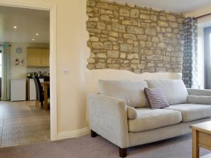sala de estar con sofá y pared de piedra en The Creamery en North Wootton