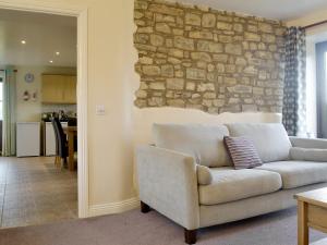 a living room with a couch and a stone wall at The Creamery in North Wootton