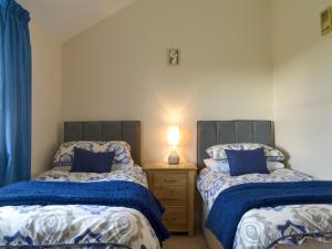 una camera con 2 letti e un comodino con lampada di The Creamery a North Wootton