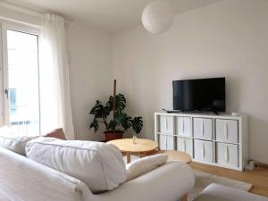 a living room with a white couch and a tv at Gemütliches Privatzimmer in geräumiger Gemeinschaftswohnung in Dresden