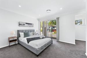 Habitación blanca con cama y ventana en AirCabin - Norwest - Luxury Lovely - 4 Beds House, en Baulkham Hills