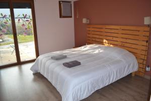 a bedroom with a white bed with a wooden headboard at Maison 3 chambres, 3 SdB, terrasse, piscine, spa in Meyrié