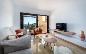 a living room with a couch and a tv at Coto Real 2412 KHIOS in San Luis de Sabinillas