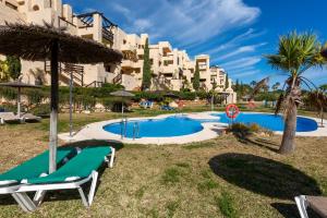 a pool with two lounge chairs and an umbrella at Coto Real 2412 KHIOS in San Luis de Sabinillas