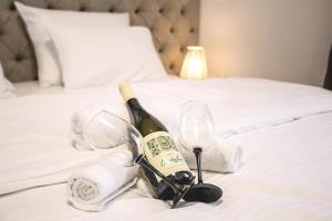 a bottle of champagne and two wine glasses on a bed at VILA MB in Ruma