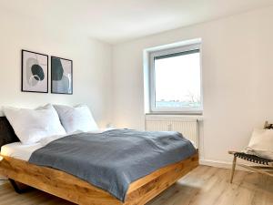 a white bedroom with a wooden bed with a window at Antoni Homes 2-4 Personen I 2 Schlafzimmer I Messe I Uni I Arena in Augsburg