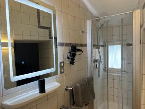 a bathroom with a sink and a mirror and a shower at Weingut Gästehaus Bach in Cochem