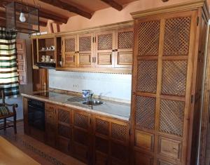 a kitchen with wooden cabinets and a sink at Apartamentos Casalpujarra in Bubión +14 photos