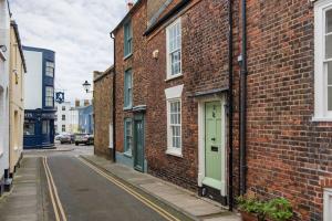 a brick building with green doors on a street at Rogue's Cottage - Secluded gem by the sea in Deal