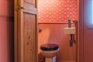 een badkamer met een toilet en een zwarte stoel bij Rogue's Cottage - Secluded gem by the sea in Deal