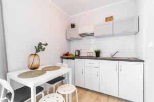 uma cozinha branca com uma pequena mesa e cadeiras em Apartamenty - Sztutowo Zalewowa em Sztutowo