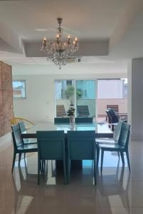 a dining room with a table and chairs and a chandelier at Cobertura COM PISCINA in Rio de Janeiro