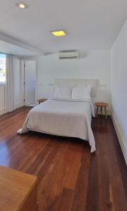 a bedroom with a white bed and a wooden floor at Cobertura COM PISCINA in Rio de Janeiro