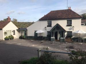 a white building with tables and umbrellas in a parking lot at The Kings Head in Dorking