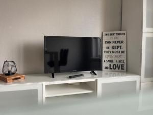 telewizor z płaskim ekranem siedzący na białym centrum rozrywki w obiekcie Gästehaus Auer Fritzi w mieście Jois