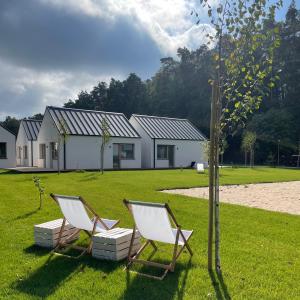 deux chaises assises dans l'herbe devant une maison dans l'établissement manō, à Barlinek