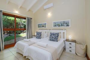 two beds in a bedroom with a window at San Lameer Villa - 14306 - 5 Bedroom Luxury - 10 pax - San Lameer Rental Agency in Southbroom +49 photos