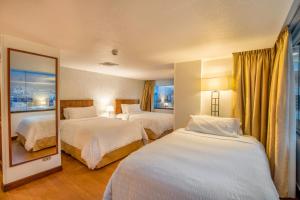 una camera d'albergo con due letti e uno specchio di Hotel Rio Amazonas a Quito