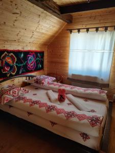 ein Schlafzimmer mit einem Bett in einem Blockhaus in der Unterkunft Cabanele Rus in Budeşti