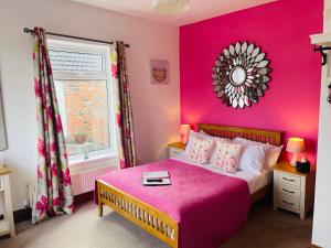 a pink bedroom with a bed and a window at The Railway Inn in Rise