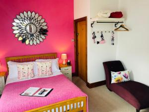 a pink bedroom with a bed and a chair at The Railway Inn in Rise
