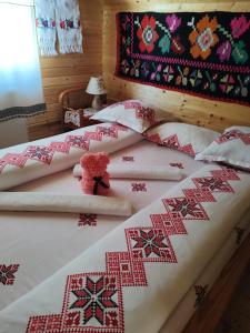 a red teddy bear sitting on top of two beds at Cabanele Rus in Budeşti