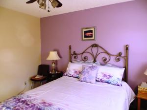 a bedroom with a white bed with purple walls at Wild Rose Bed & Breakfast in Saskatoon